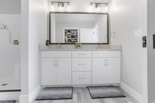 bathroom with a shower, vanity, and wood-type flooring