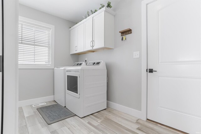 laundry room featuring washer and clothes dryer, cabinets, and light wood-type flooring