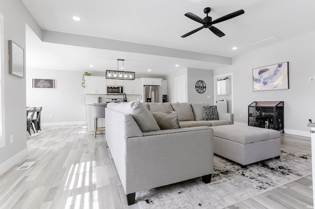 living room with ceiling fan and light hardwood / wood-style flooring