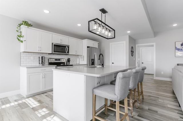 kitchen featuring backsplash, a kitchen island with sink, sink, white cabinetry, and stainless steel appliances