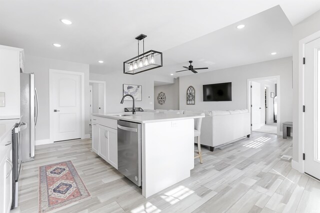 kitchen featuring white cabinetry, sink, ceiling fan, stainless steel appliances, and a kitchen island with sink