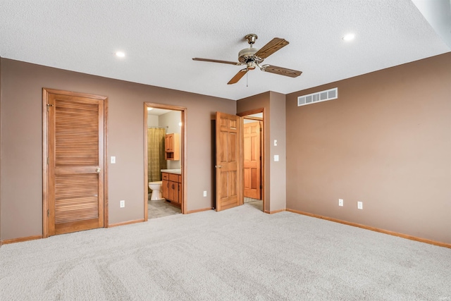 unfurnished bedroom featuring light carpet, a textured ceiling, connected bathroom, and ceiling fan