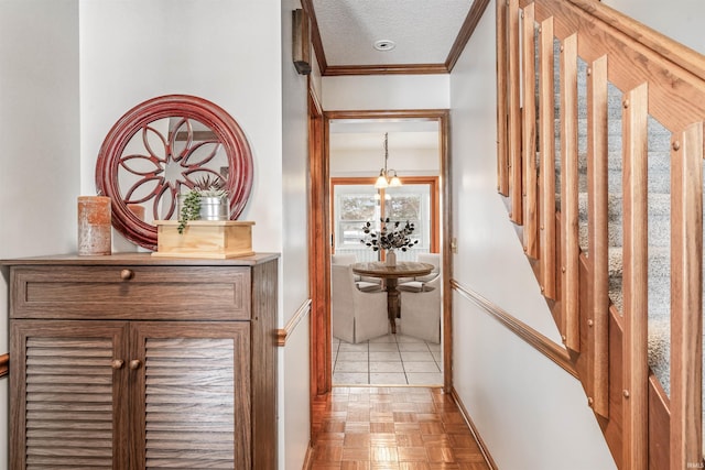 hall featuring ornamental molding, a textured ceiling, light parquet floors, and a notable chandelier