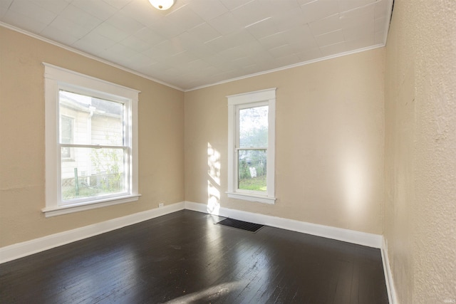 empty room with dark hardwood / wood-style floors and crown molding