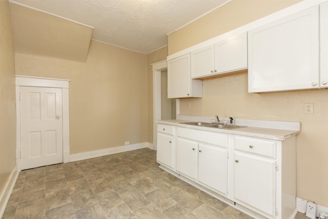 kitchen with white cabinetry, sink, and a textured ceiling