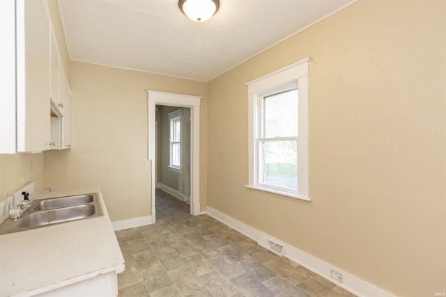 kitchen with white cabinets, sink, and a textured ceiling