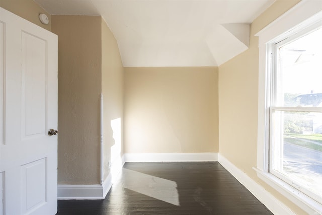 corridor with dark hardwood / wood-style floors and vaulted ceiling