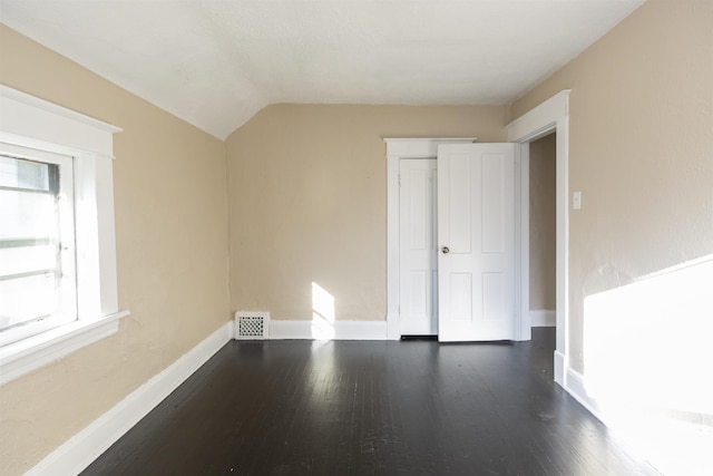 additional living space featuring dark hardwood / wood-style floors, a healthy amount of sunlight, and lofted ceiling