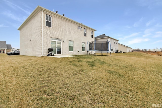 back of house with a yard, a trampoline, and a patio area