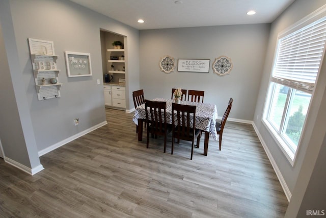 dining room featuring wood-type flooring and built in shelves