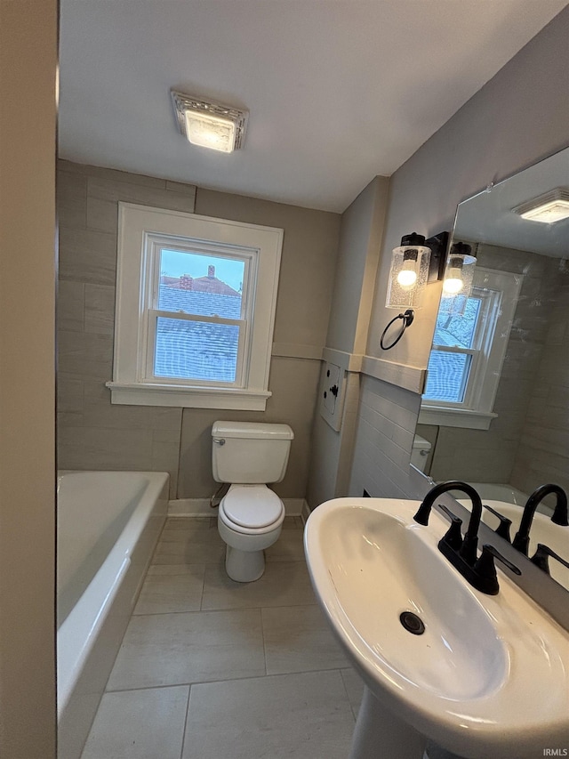 bathroom with tile patterned floors, toilet, a bathing tub, and sink