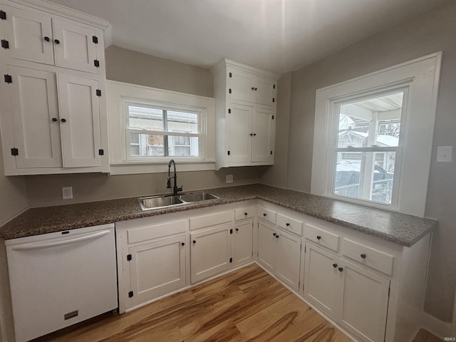 kitchen with white dishwasher, white cabinets, sink, and light hardwood / wood-style flooring