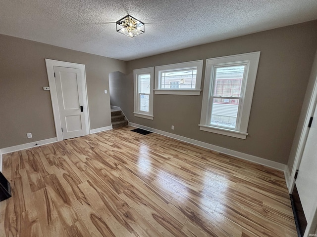 unfurnished room featuring a textured ceiling and light wood-type flooring