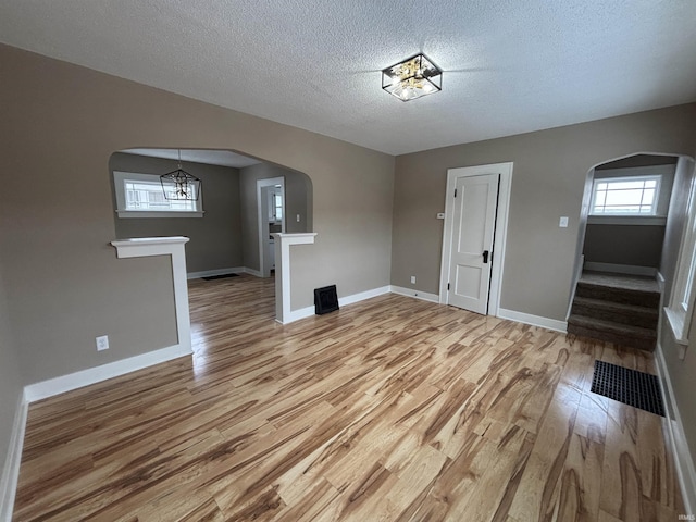 unfurnished living room with a textured ceiling and light wood-type flooring