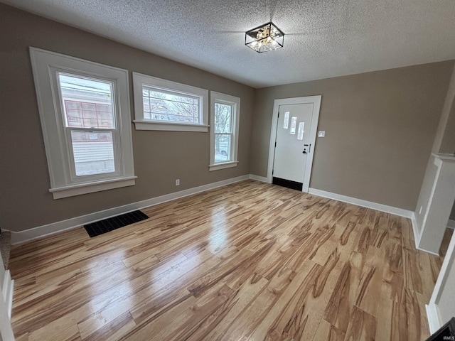 entrance foyer featuring a textured ceiling, light hardwood / wood-style floors, and plenty of natural light