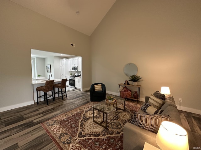 living room with dark hardwood / wood-style flooring, high vaulted ceiling, and sink