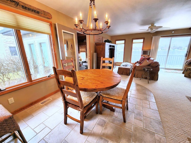 dining area with ceiling fan with notable chandelier and light carpet