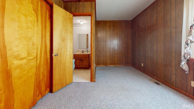 carpeted bedroom featuring wood walls and sink