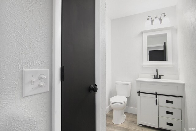 bathroom with toilet, vanity, and hardwood / wood-style flooring