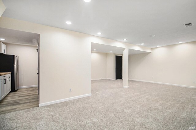 basement with light colored carpet and stainless steel refrigerator