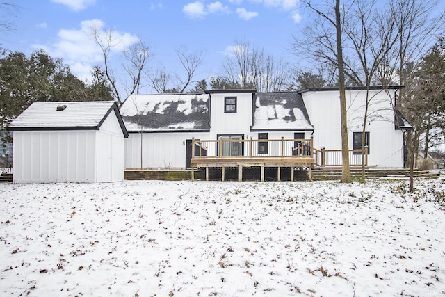 snow covered property with a storage shed and a wooden deck