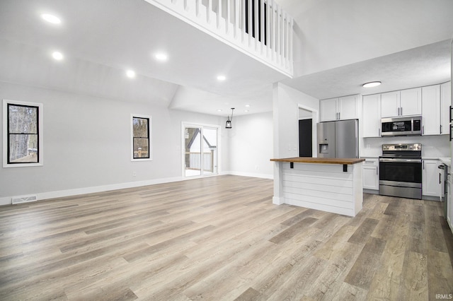 kitchen featuring white cabinets, appliances with stainless steel finishes, light hardwood / wood-style flooring, and butcher block counters