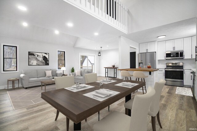 dining room with light hardwood / wood-style floors and a towering ceiling