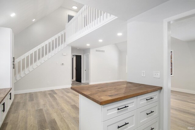 kitchen featuring white cabinets, wooden counters, vaulted ceiling, and light hardwood / wood-style floors