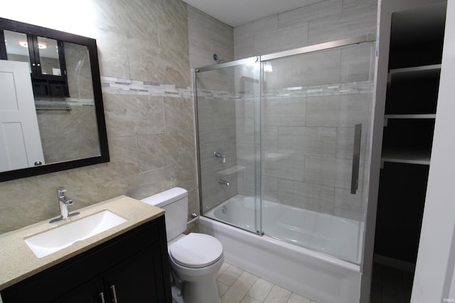 full bathroom featuring vanity, toilet, tile walls, and bath / shower combo with glass door