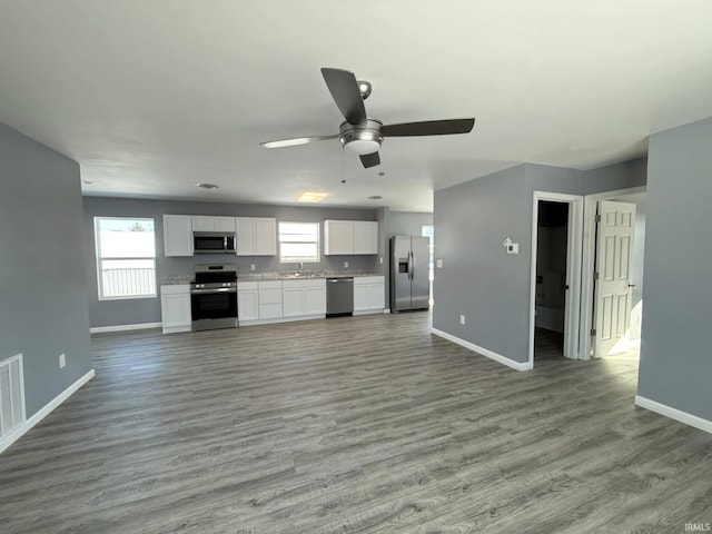 kitchen with white cabinets, light wood-type flooring, stainless steel appliances, and ceiling fan