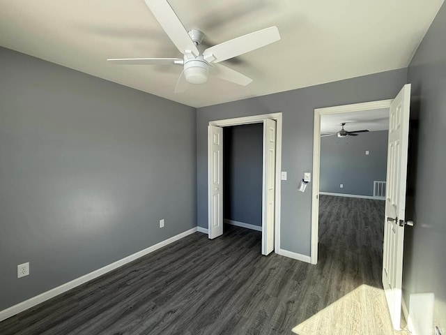 unfurnished bedroom featuring ceiling fan, a closet, and dark wood-type flooring