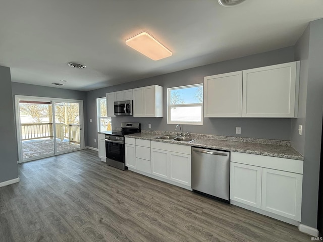 kitchen featuring white cabinetry, sink, a healthy amount of sunlight, wood-type flooring, and appliances with stainless steel finishes