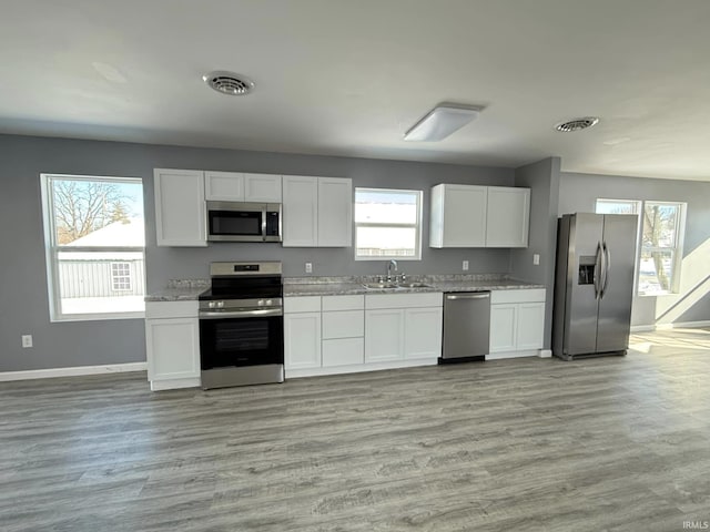 kitchen featuring sink, white cabinets, light hardwood / wood-style floors, and appliances with stainless steel finishes