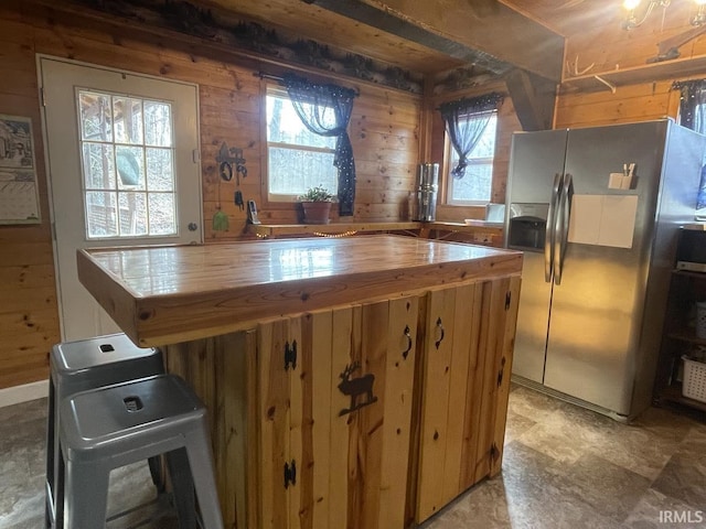 kitchen with wood counters, wood walls, and stainless steel refrigerator with ice dispenser