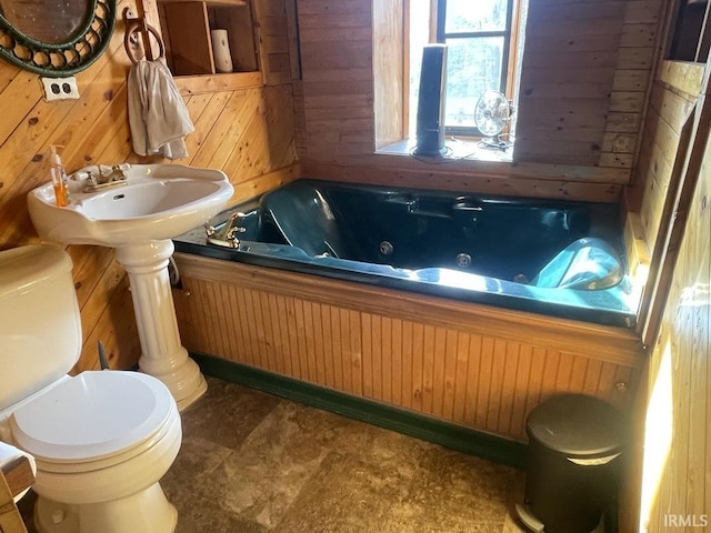 bathroom featuring a tub, wooden walls, and toilet