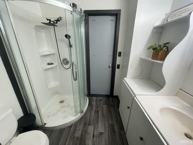 bathroom with hardwood / wood-style floors, vanity, toilet, and an enclosed shower