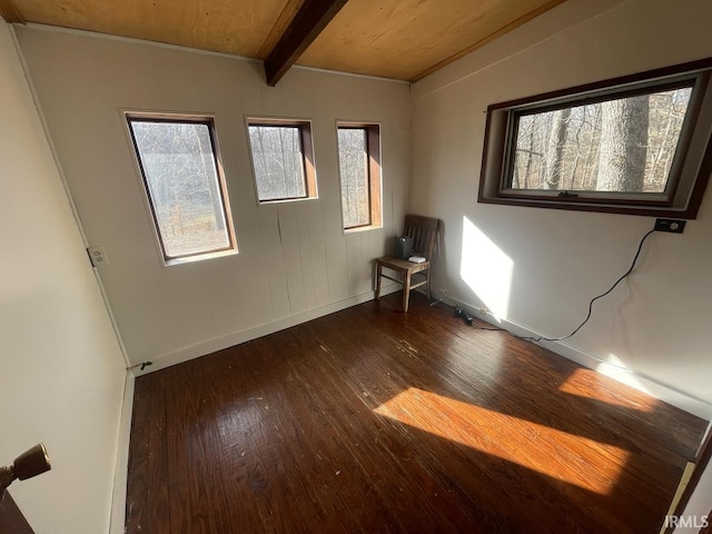 unfurnished room featuring beamed ceiling and dark hardwood / wood-style floors