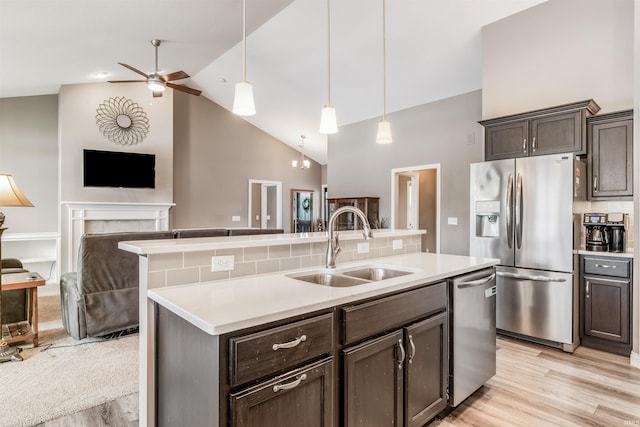 kitchen featuring tasteful backsplash, stainless steel appliances, sink, decorative light fixtures, and high vaulted ceiling