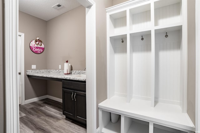 mudroom featuring hardwood / wood-style flooring, sink, and a textured ceiling