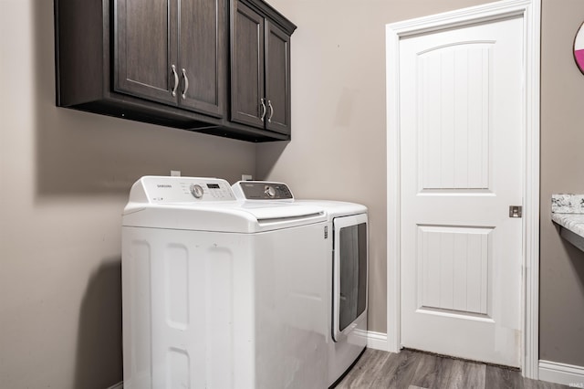 washroom featuring washer and dryer, cabinets, and wood-type flooring