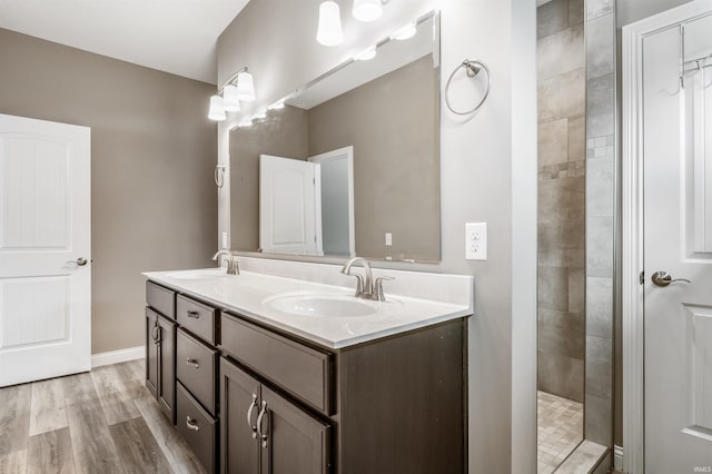 bathroom featuring vanity, a tile shower, and wood-type flooring