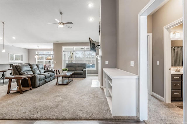 carpeted living room featuring ceiling fan and sink