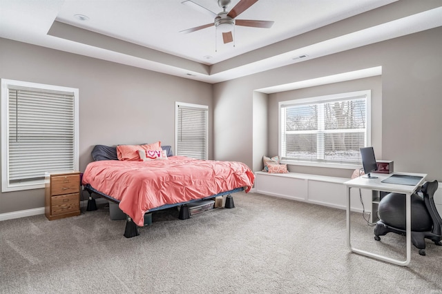 carpeted bedroom featuring ceiling fan and a tray ceiling