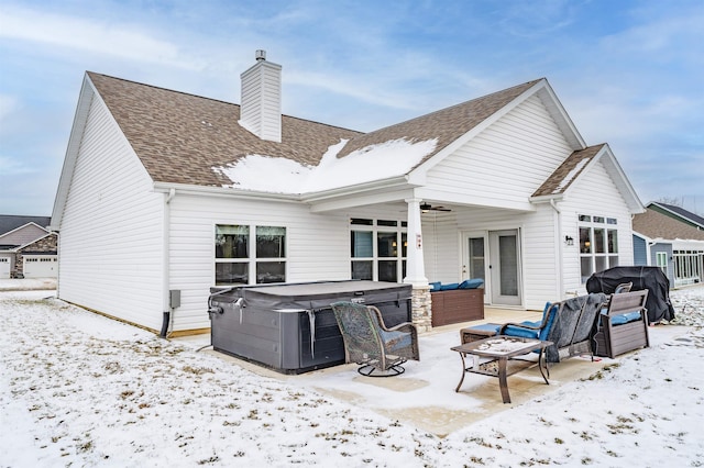 snow covered house with an outdoor living space, ceiling fan, and a hot tub