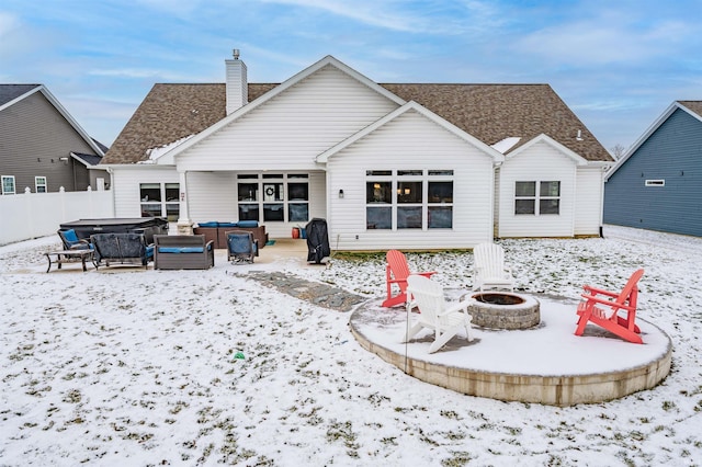 snow covered property featuring a hot tub and an outdoor fire pit