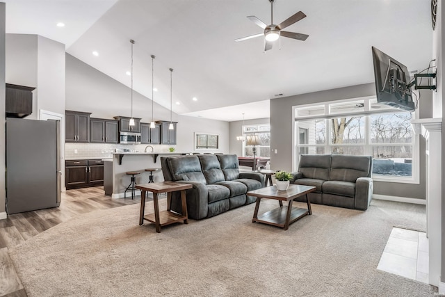 living room featuring high vaulted ceiling and ceiling fan with notable chandelier