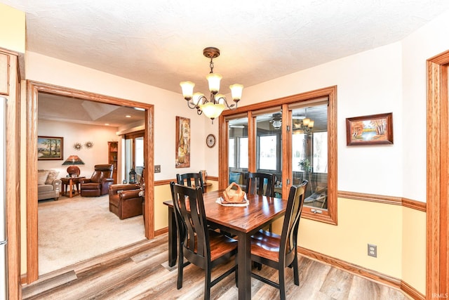 dining space with light wood-type flooring and a notable chandelier