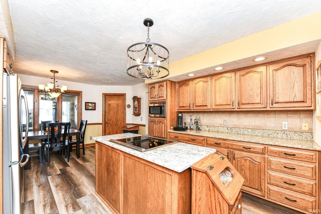 kitchen featuring a kitchen island, stainless steel appliances, hanging light fixtures, and a chandelier