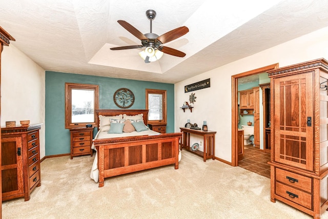 carpeted bedroom with a textured ceiling, a tray ceiling, and ceiling fan