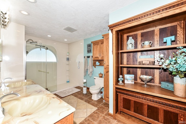 bathroom with tile patterned floors, a textured ceiling, vanity, a shower, and toilet